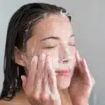 little bumps on forehead: woman using anti dandruff shampoo for face