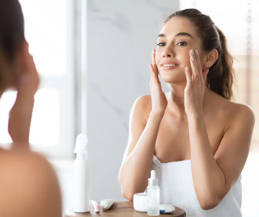 Woman in her 20s applying skincare products to maintain healthy, glowing skin